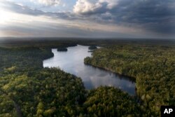 FILE - Woodlands surround Peaked Mountain Pond near the site of a proposed largest-in-the-world flagpole, near Columbia Falls, Maine, Thursday, April 27, 2023. (AP Photo/Rodrique Ngowi)