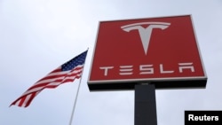 FILE - The Tesla logo is visible atop a charging station in Salt Lake City, Utah, Sept. 28, 2017.