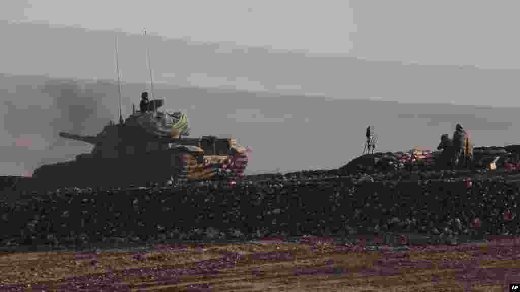 Turkish soldiers on a tank, left, move to a new position as others, right, man a mortar unit during fighting between Syrian Kurds and the militants of Islamic State group, landed within Turkey, on the outskirts of Suruc, at the Turkey-Syria border, Oct. 1