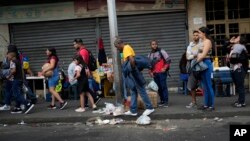 Varias personas hacen fila mientras esperan un transporte público en Caracas, Venezuela, el lunes 27 de febrero de 2023. (Foto AP/Ariana Cubillos)