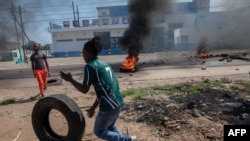 FILE - A protester rolls a tire to burn during a protest in the Choupal neighborhood of Maputo, Mozambique, Nov. 15, 2024. 