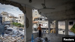 Seorang anak laki-laki berdiri di dalam rumahnya yang rusak akibat serangan Israel setelah gencatan senjata antara Israel dan Hizbullah di Tyre, Lebanon, Jumat, 29 November 2024. (Foto: Adnan Abidi/Reuters)