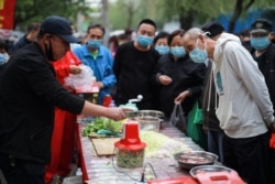 A vendor demonstrates a food processor to customers at a market in Shenyang in China's northeastern Liaoning province on May 12, 2020.