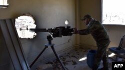 A fighter from the Syrian pro-government forces mans a gun inside damaged houses as they approach the Baeedin district in eastern Aleppo, near Masaken Hanano, November 23, 2016.