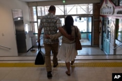 FILE - Kenneth Barthel, left, who was adopted to the United States astatine  property  6, and his wife, Napela, comfortableness  each   different   arsenic  they permission  the Busan Metropolitan City Child Protection Center successful  Busan, South Korea, May 17, 2024, aft  searching for documents related to his commencement  family.