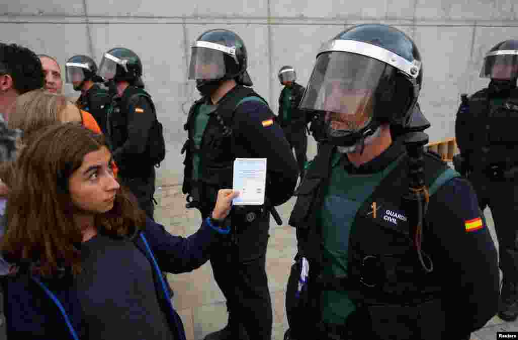 Una mujer muestra una boleta a un oficial de la Guardia Civil española fuera de una mesa de votación para el referéndum de independencia prohibido en Sant Julia de Ramis, el 1 de octubre de 2017. 