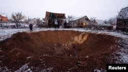 A local resident stands next to a crater at a site of a Russian missile strike, amid Russia's attack on Ukraine, in Kyiv, Ukraine Dec. 11, 2023. 