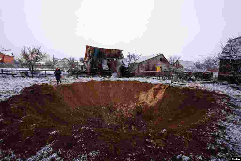 A local resident stands next to a crater at a site of a Russian missile strike in Kyiv, Ukraine.