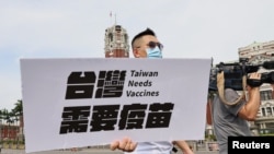 A lawmaker from Taiwan's main opposition Kuomintang (KMT) Party holds signs calling for the government to accept all vaccines and provide free vaccines for all citizens, in front of the Presidental building in Taipei, Taiwan, June 4, 2021. 