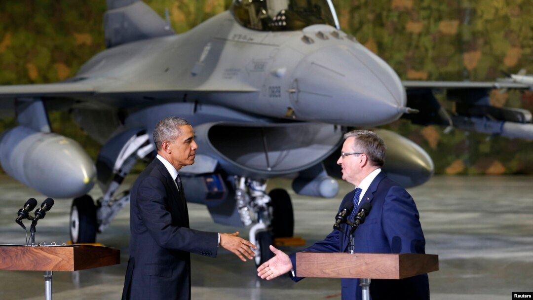 With an F-16 fighter in the background, U.S. President Barack Obama and Poland's President Bronislaw Komorowski (R) shake hands upon Obama's arrival at Chopin Airport in Warsaw, June 3, 2014.