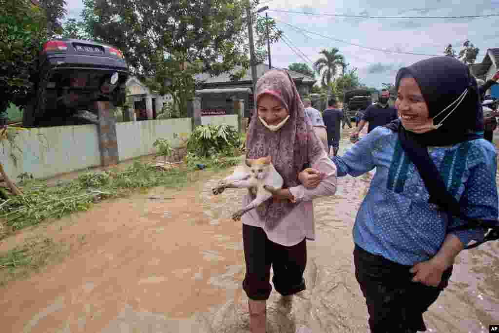 این دو زن اندونزیایی و گربه آنها از سیلاب ناشی از بارش باران‌های سیل آسا در شهر مدان نجات یافته اند.