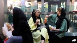 People have their lunch in a shopping center at the Tehran's Grand Bazaar in Iran, June 10, 2020. As businesses open, health experts fear a growing complacency among 80 million people may further allow the virus to spread.