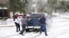 Residentes ayudan al conductor de una camioneta a salir del hielo en la carretera en Round Rock, Texas, el 17 de febrero de 2021, después de una tormenta invernal. 