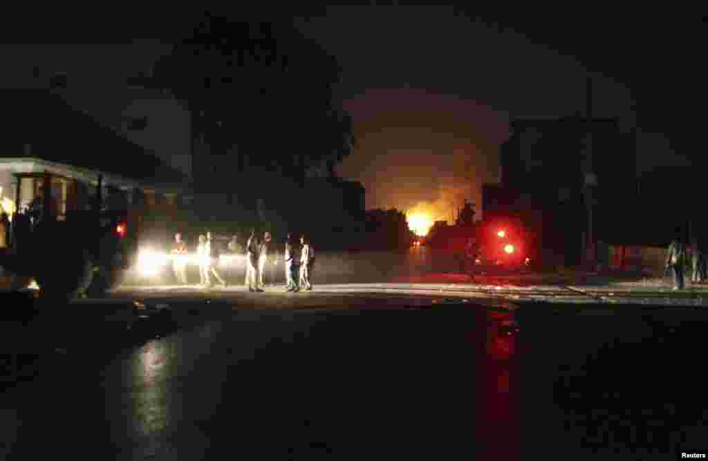 Libya Shield Force members are seen near a building on fire, which witnesses said was hit by a rocket, after clashes between rival militias in the Sarraj district of Tripoli, Aug. 23, 2014. 