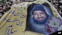 Supporters of religious group Sunni Tehreek hold a huge poster of Mumtaz Qadri, the confessed killer of a liberal Pakistani governor, during a rally to condemn the court decision against Qadri, October 1, 2011 in Karachi.