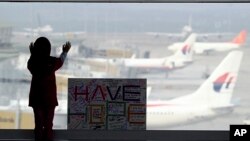 A girl stands next to a sign board at Kuala Lumpur International Airport in Sepang, Malaysia, March 10, 2014.
