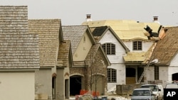 A construction worker puts a roof on a house in a western suburb of Chicago, (File).