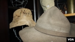 Des centaines de chapeaux et casques de champs de bataille conservés dans un « depot de la guerre » ... y compris le chapeau en arrière-plan qui appartenait à un soldat tué en arrière-plan en conflit dans ce qui est maintenant la Namibie dans les années 1980. (D. Taylor / VOA)