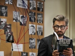 Grzegorz Rzeczkowski, an investigative reporter for the weekly Polish newsmagazine Polityka, poses with a book he has written about an eavesdropping affair that helped toppled a government, in Warsaw, Poland, June 28, 2019.
