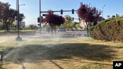 Sprinklers water grass near a street corner Friday, April 9, 2021, in the Summerlin neighborhood of northwest Las Vegas. (AP Photo/Ken Ritter)