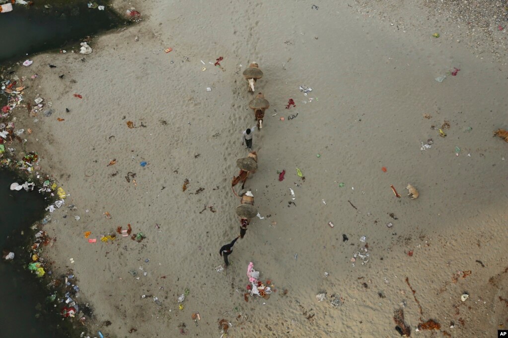 인도 잠무의 오염된 타위 강 둑에서 남성들이 모래를 모으고 있다.