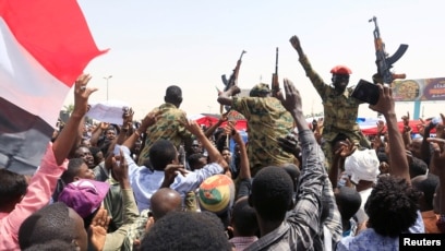 FILE - Sudanese military officers and demonstrators ride atop a military tanker as they protest against the army's announcement that President Omar al-Bashir would be replaced by a military-led transitional council, in Khartoum, Apr. 12, 2019. 