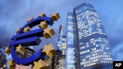 FILE - The euro sculpture stands in front of the European Central Bank, right, in Frankfurt, Germany.