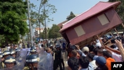People carry a giant model of a house toward police as they protest government-sanctioned evictions, World Habitat Day, Phnom Penh, Oct. 10, 2013.