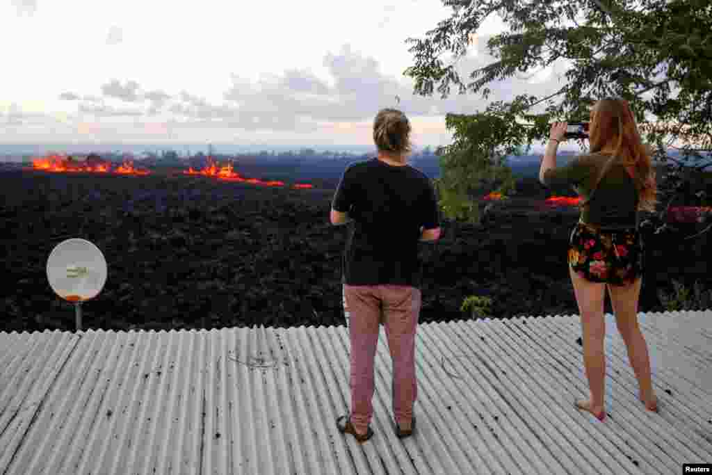 Dua warga AS naik ke atas atap rumahnya mengambil gambar lahar di pinggiran kota Pahoa, saat letusan gunung Kilauea di Kepulauan Hawaii.