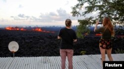 Jolon Clinton, (izquierda), y su hermana Halcy, toman fotos de una fisura del volcán Kilauea cerca de su casa en las afueras de Pahoa, Hawái, el lunes, 14 de mayo, de 2018.