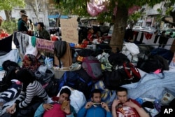 Migrants rest under a tree at the Victoria Square in Athens, Greece, March 1, 2016.