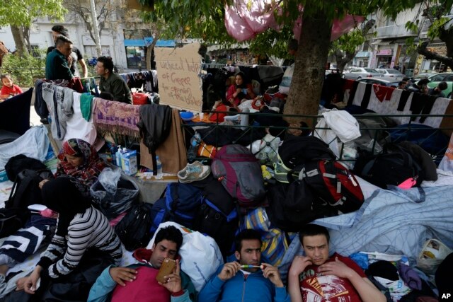 Migrants rest under a tree at the Victoria Square in Athens, Greece, March 1, 2016.