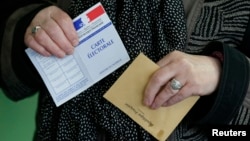 A woman prepares to cast her ballot at a polling station in Henin-Beaumont, northern France, March 29, 2015. France goes to the polls in a two-round departmental election for local officials on March 22 and March 29. 