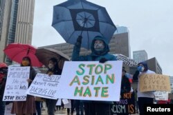 FILE - People hold placards as they gather to protest anti-Asian hate crimes, racism and vandalism, outside City Hall in Toronto, Ontario, Canada, March 28, 2021.