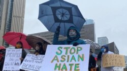 FILE - People hold placards as they gather to protest anti-Asian hate crimes, racism and vandalism, outside City Hall in Toronto, Ontario, Canada, March 28, 2021.