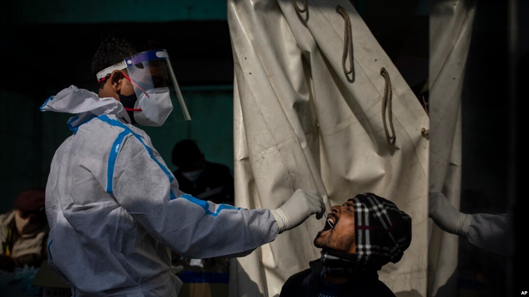 Petugas kesehatan mengambil sampel swab penumpang untuk tes COVID-19 di stasiun kereta api di New Delhi, India, Kamis, 30 Desember 2021. (Foto: AP/Altaf Qadri)