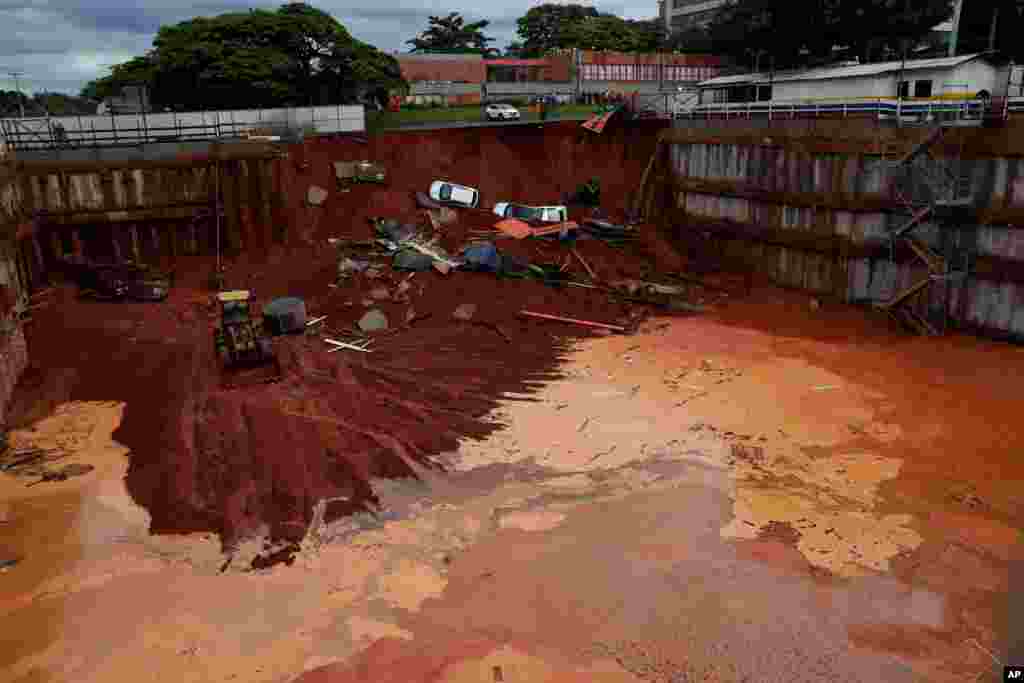 Vehicles lay at the bottom of a construction site after a road collapsed due to heavy rains in the center of Brasilia, Brazil, Dec. 10, 2019.