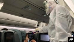 A worker in a hazardous materials suit takes the temperature of a passenger on a Cathay Pacific flight from Hong Kong to Rome after it landed at Rome Fiumicino Airport in Rome, Italy, Friday, Jan. 31, 2020. The U.S. advised against all travel to…