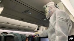 A worker in a hazardous materials suit takes the temperature of a passenger on a Cathay Pacific flight from Hong Kong to Rome after it landed at Rome Fiumicino Airport in Rome, Italy, Jan. 31, 2020. 