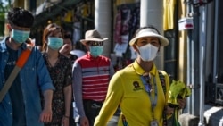 A Thai tour guide (R) escorts Chinese tourists wearing face masks near the Grand Palace in Bangkok on January 27, 2020. - Thailand has detected eight Coronavirus cases so far -- three of whom are receiving treatment in hospital and five of whom have been