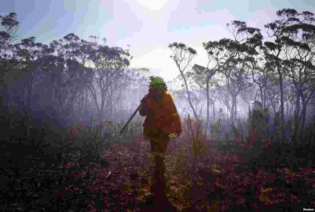 A female Rural Fire Service firefighter walks through a burnt area after trying to extinguish a small fire approaching homes near the Blue Mountains suburb of Blackheath, west of Sydney, Oct. 23, 2013. 