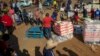 Des personnes touchées par le ralentissement économique du au coronavirus reçoivent des dons de nourriture dans le quartier d'Iterileng près de Laudium, au sud-ouest de Pretoria, Afrique du Sud, le 20 mai 2020.