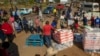 FILE - People affected by the coronavirus economic downturn receive food donations at the Iterileng informal settlement near Laudium, southwest of Pretoria, South Africa, May 20, 2020.