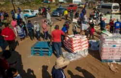 People affected by the coronavirus economic downturn, receive food donations at the Iterileng informal settlement near Laudium, southwest of Pretoria, South Africa, May 20, 2020.