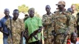 Government and opposition soldiers pose for a picture in the government barracks in Kajo Keji town, where 10 opposition soldiers were staying with the government troops in a makeshift soldier swap, in Kajo Keji county, South Sudan, Jan. 6, 2019.