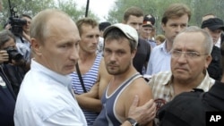 Russian PM Vladimir Putin (l) meets with people, who suffered from forests fires which swept the area in the village of Verkhnyaya Vereya, 30 Jul 2010
