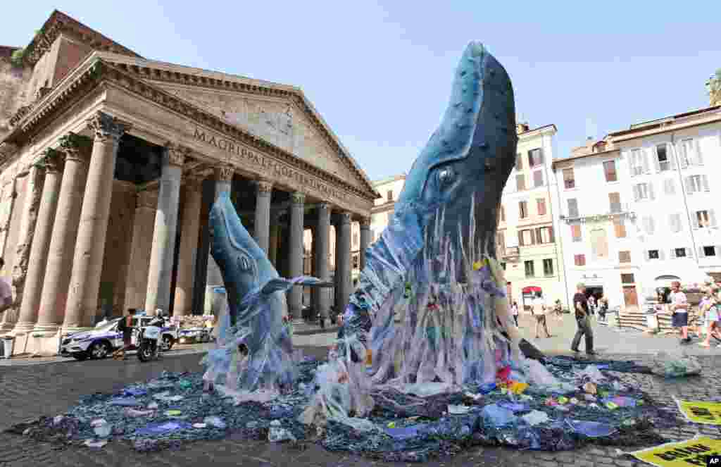 A sculpture shows the life-size reproduction of two whales emerging from a sea filled with plastic waste, in front of the Pantheon, in Rome, Italy.