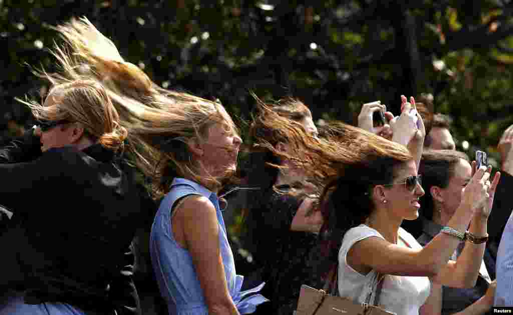 Guests, with their hair blown back, watch while Marine One takes off as U.S. President Barack Obama departs the White House in Washington. Obama is traveling to New Orleans to commemorate the 10th anniversary of Hurricane Katrina.