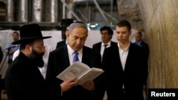 FILE - Israel's Prime Minister Benjamin Netanyahu (C) reads a prayer with Western Wall Rabbi Shmuel Rabinowitz (L) as his son Yair (R) stands next to him, at the Western Wall, Judaism's holiest prayer site, in Jerusalem's Old City.