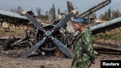 A pro-Russian rebel walks by a burnt-out plane at the destroyed airport in Luhansk, eastern Ukraine, Sept. 14, 2014. 